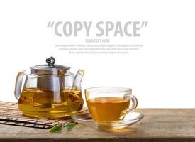 Warm cup of tea and glass jars with organic green tea leaf on wooden table isolate white background with copy space photo