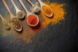 Herbs and spices and the spoon over black stone background. Top view photo