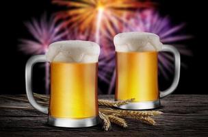 Two Glasses of Light Beer with wheat on the wooden table with fireworks background, with copy space for your text photo