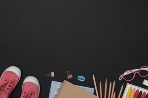 Creative flatlay of education green table with student books, shoes, colorful crayon, eye glasses, empty space on blackboard background, Concept of education and back to school photo