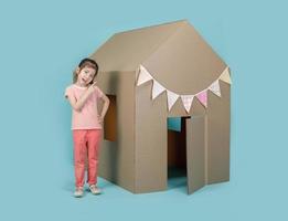 Asian little child girl playing with cardboard house isolated on blue long banner, Creative at home with family concept photo