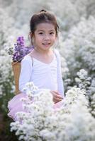 linda niña sonriente usa un traje de hada de ballet mágico en el hermoso campo de flores blancas de margaret. foto