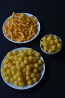 Corn salted and peppered chips on a white plate. Delicious breakfast of corn chips on a black background. photo