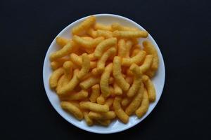 chips de maíz salados y con pimienta en un plato blanco. delicioso desayuno de chips de maíz sobre un fondo negro. foto