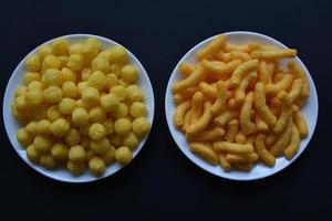 Corn salted and peppered chips on a white plate. Delicious breakfast of corn chips on a black background. photo