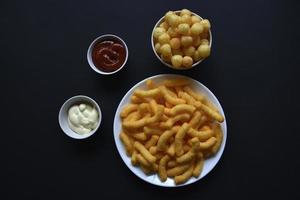 Peppered corn chips with sauce on a black background. Salty snack of corn snacks close-up. photo