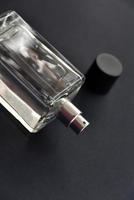 A glass bottle with perfume on a black background. A beautiful bottle with a perfume spray dispenser. photo