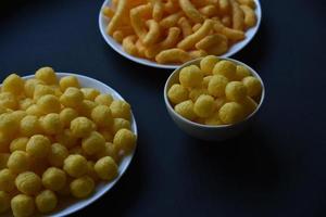 chips de maíz salados y con pimienta en un plato blanco. delicioso desayuno de chips de maíz sobre un fondo negro. foto