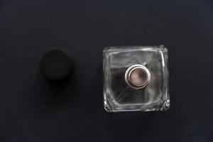 A glass bottle with perfume on a black background. A beautiful bottle with a perfume spray dispenser. photo