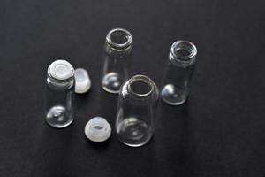 Glass empty bottles on a black background close-up. Pharmacy bottles in the afternoon in a group. photo