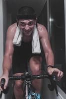 Man cycling on the machine trainer he is exercising in the home at night playing online bike racing game photo