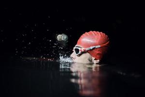 nadador triatleta auténtico que tiene un descanso durante el entrenamiento duro en la noche foto