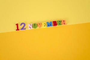 November 12 on a yellow, paper background with wooden and multicolored letters with space for text. photo