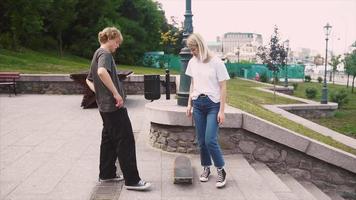 Two young people practice skateboarding on flat concrete between steps video
