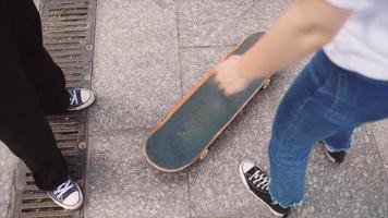 Two young people practice skateboarding footwork on concrete video