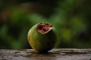 primer plano de un delicioso juego de guayaba con hojas verdes frescas sobre una mesa de madera y fondo verde de la naturaleza foto