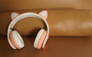 White wireless headphones on a brown leather background, divided in two halves. Flat lay. photo