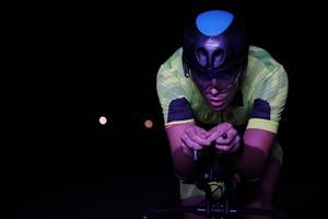 atleta de triatlón montando bicicleta rápido por la noche foto