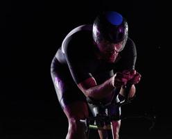 atleta de triatlón montando bicicleta rápido por la noche foto