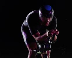 triathlon athlete riding bike fast at night photo