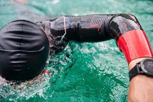 triathlon athlete swimming on lake wearing wetsuit photo