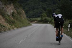 atleta de triatlón montando una bicicleta vestida de negro foto