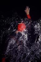 atleta de triatlón nadando en la noche oscura con traje de neopreno foto
