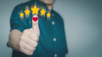 mano de hombre con icono de corazón rojo y cinco estrellas doradas. concepto de satisfacción en la experiencia del cliente en el uso del servicio. foto