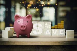 Pink piggy bank with SAVE words on wooden cube in abstract bokeh interior cafe backdrop. Business finance concept of planning, saving money wealth, financial and investment. photo