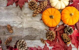 Festive autumn decor from pumpkins, pine and leaves on a  wooden background. Concept of Thanksgiving day or Halloween. Flat lay autumn composition with copy space.