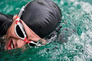 triathlon athlete swimming on lake wearing wetsuit photo