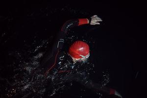 atleta de triatlón nadando en la noche oscura con traje de neopreno foto