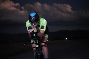 triathlon athlete riding bike fast  at night photo