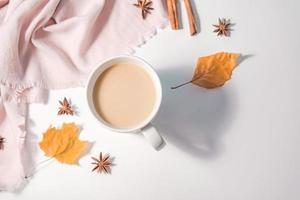 concepto de otoño o invierno con hojas de pino y arce, taza de café, canela y bufanda, puesta plana, vista superior. foto