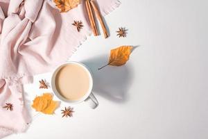 concepto de otoño o invierno con hojas de pino y arce, taza de café, canela y bufanda, puesta plana, vista superior. foto