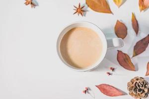 concepto de otoño o invierno con hojas de pino y arce, taza de café, canela y bufanda, puesta plana, vista superior. foto