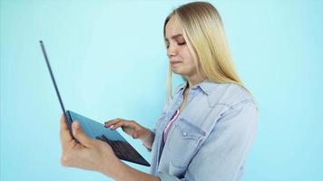 giovane donna utilizzando un' il computer portatile nel davanti di un' leggero blu sfondo video