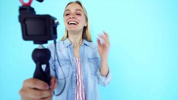 Vlogger verwendet Kamera und Selfie-Stick, um Videoblogs vor blauem Hintergrund aufzunehmen video