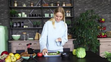 mujer joven en una cocina con ingredientes frescos y dispositivo de teléfono inteligente video