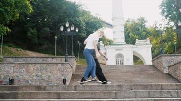 Teenage boy and girl hanging out at the park with a skateboard video