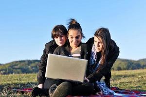 grupo de adolescentes trabajando en una laptop al aire libre foto