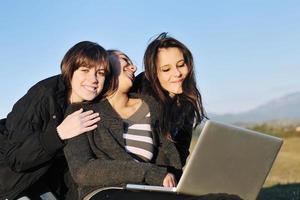 grupo de adolescentes trabajando en una laptop al aire libre foto