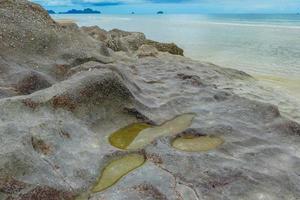 Seaside rocks on the beautiful beach in the morning with rain cloud. photo