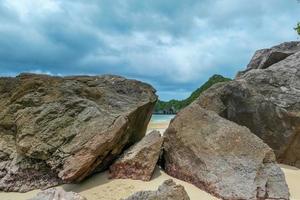 Seaside rocks on the beautiful beach in the morning with rain cloud. photo