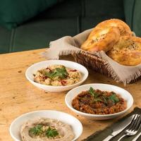 Mediterranean dishes, baba ganoush, muhammara and hummus with a basket of bread photo