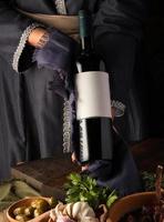 A vertical shot of a person in a traditional costume showing a wine bottle photo