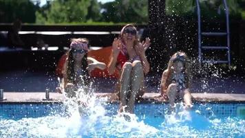 Adult woman and children splash at edge of pool video