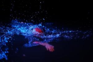 atleta de triatlón real nadando en la noche oscura foto