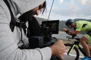 cinematographer taking action shot of triathlon bike athlete photo