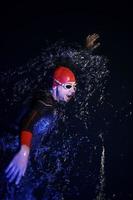 real triathlon athlete swimming in dark night photo